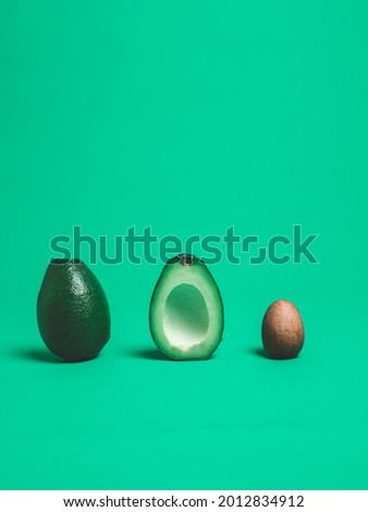Vertical Photo of Avocados Cut in Half Put in a Row with a Green Background.