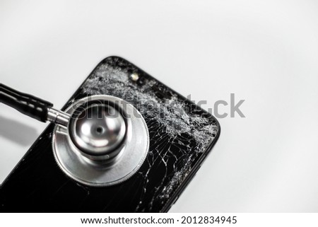 black mobile phone with broken screen and stethoscope,selective focus,isolated on white background.Cell phone crash From the high point of the screen cracked.