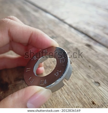 a picture of a spoke wrench or spoke tool set in metallic color with a wooden table background Royalty-Free Stock Photo #2012836169