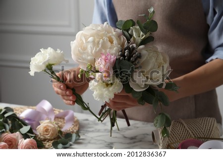Florist creating beautiful bouquet at white marble table, closeup Royalty-Free Stock Photo #2012836367
