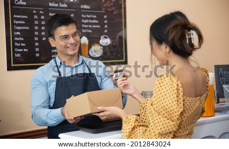 Professional Barista small business owner taking woman customer credit card for payment an order. Small business cafe and bakery owners concept.
