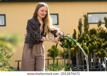 Female gardener watering the plants in the greenhouse