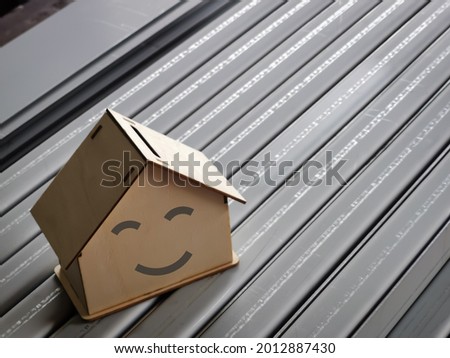 Mortgage business concept. Smile face on wooden house miniature against blurry background.
