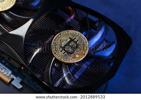 Video card with a gold coin Bitcoin on the cooler close-up. The concept of mining and mining of cryptocurrency, the device of a cryptocurrency farm.