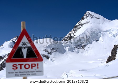 Danger sign beware of crevasse on a sunny summer day at Jungfraujoch. Photo taken July 20th, 2021, Lauterbrunnen, Switzerland.
