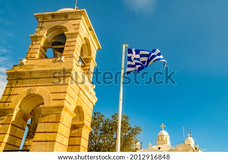 Greece flag flaming besides bell tower of saint isidore holy church, lycabettus hill, athens, greece