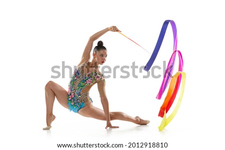 Young graceful girl, female rhythmic gymnast training with bright colored ribbon isolated over white studio background. Concept of action, motion, sport life, competition.