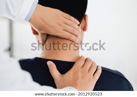 physiotherapist massage therapist holding male client's head and massaging tight neck muscles the result of prolonged use of mobile phones.Office Syndrome Royalty-Free Stock Photo #2012920523
