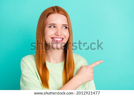 Photo portrait of red haired girl smiling pointing finger copyspace isolated vivid teal color background