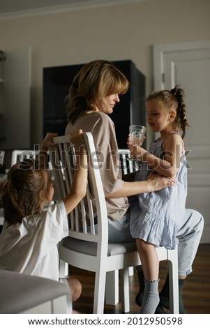 Young beautiful mother with two pretty daughters on the kitchen. Happy family breakfast. Stylish interior. Good relationships. Funny children. Love and care.  Europeans.  Live and natural picture