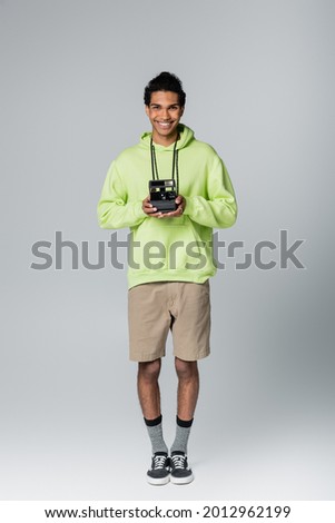 full length view of stylish african american man with vintage camera isolated on grey