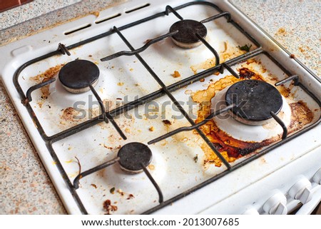 Dirty grease stove with food leftovers. Unclean gas kitchen cooktop with greasy spots, old fat stains, fry spots and oil splatters. Royalty-Free Stock Photo #2013007685