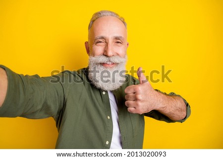 Photo portrait of grandfather taking selfie on camera smiling showing like sign isolated vivid yellow color background
