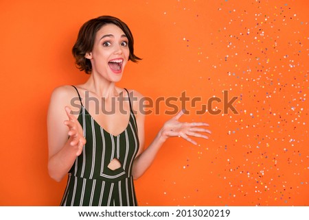 Photo of young girl happy positive smile amazed shocked surprise air fly confetti party isolated over orange color background