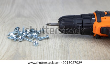 Cordless combi drill for used as normal drill, impact drill and screw driver and self-tapping screws for wood on white wooden background. Selective focus Royalty-Free Stock Photo #2013027029