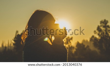 silhouette of girl taking a picture at sunset