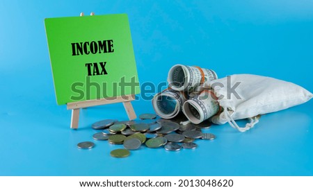 Financial concept, money, coin and clock with selective focus on tax wording isolated on blue background. 