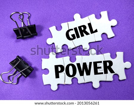 Text GIRL POWER on jigsaw puzzle with paper clips on a purple background.