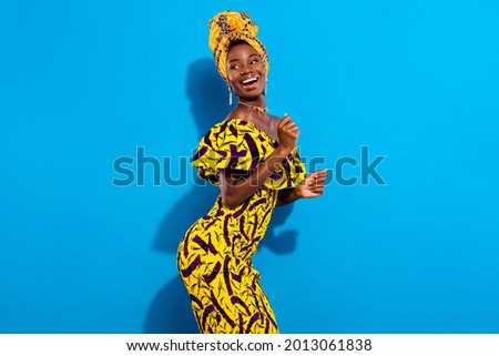 Photo of young smiling positive funky african girl dancing in yellow print dress look copyspace isolated on blue color background Royalty-Free Stock Photo #2013061838