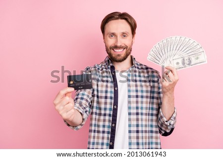 Photo of young man happy positive smile bank card money dollars income profit isolated over pink color background
