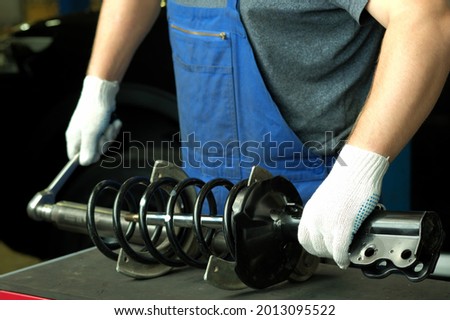 Car spare parts. Replacement of the front spring and shock absorber on a passenger car at the service center. Repair and maintenance in a car service station. Royalty-Free Stock Photo #2013095522