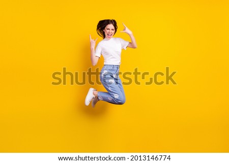 Full length profile side photo of young girl happy positive smile jump up show rock sign isolated over yellow color background