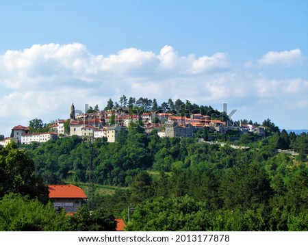 View of old town of Stanjel in the municipality of Komen in Littoral region of Slovenia on top of a hill with a forest bellow and a sign with the name partial name of the town stanjel