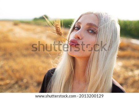 Outdoor portrait of young cute funny girl with wheat spike int he mouth.