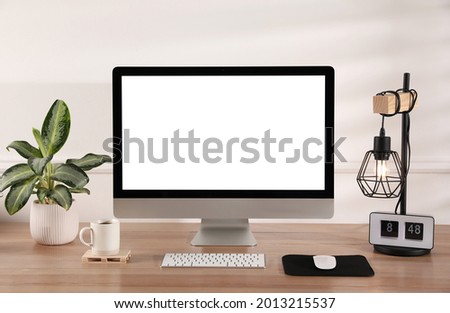 Modern computer with blank monitor screen and peripherals on wooden table indoors