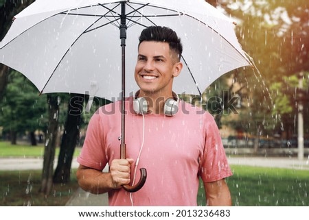 Man with umbrella walking under rain in park
