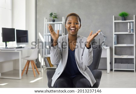 Happy black woman clapping hands sitting on modern office chair. Webcam portrait smiling overjoyed business lady in suit applauding congratulating you on successful presentation, conference or webinar Royalty-Free Stock Photo #2013237146