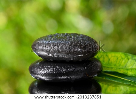 Spa massage stones on a fresh green background stock images. Spa and wellness frame stock images. Pile of black stones photo. Spa concept with zen stones