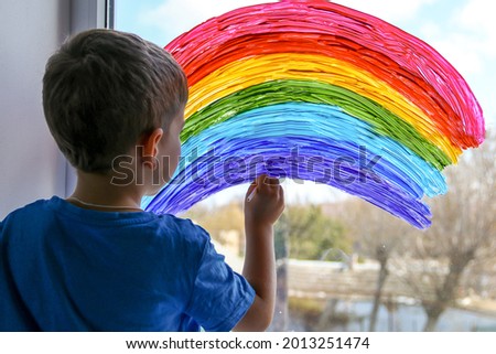 Child at home draws a rainbow on the window. Flash mob society community on self-isolation quarantine pandemic coronavirus. Children create artist paints creativity vacation 