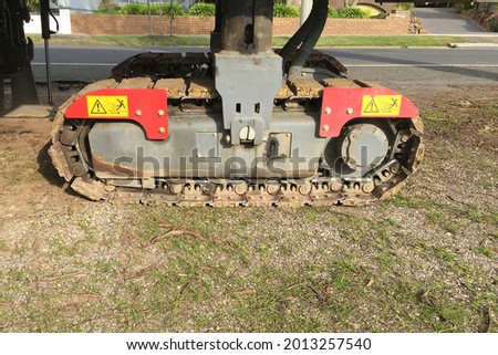 Red and yellow warning signs near the hydraulic chain of a driveable asphalt and bitumen tamping machine Royalty-Free Stock Photo #2013257540