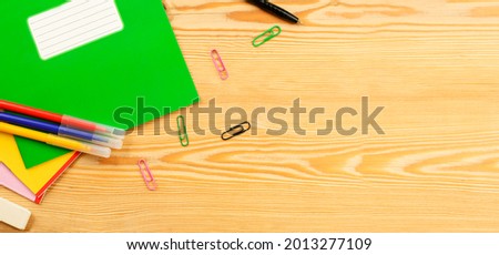 notebook, paper clips, felt-tip pens and a pen on a wooden background. view from above