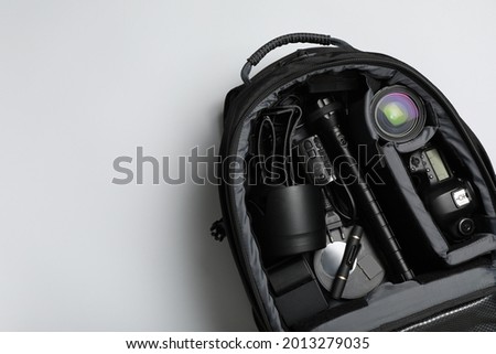 Professional photography equipment in backpack on grey background, top view. Space for text
