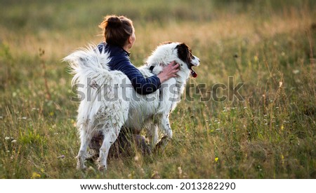 woman with dog playing in autumn landscape