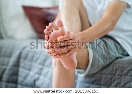 Foot pain, man suffering from feet ache in home interior, podiatry concept Royalty-Free Stock Photo #2013306155