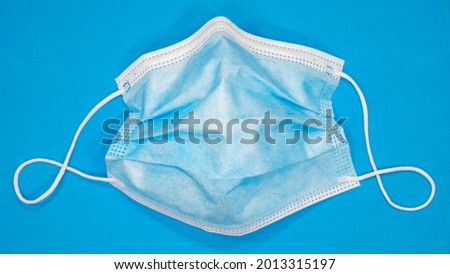 Used surgical mask on a blue background.