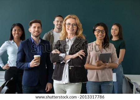 Happy senior businesswoman, diverse business team leader posing with multiethnic group of employees. Corporate teacher, mentor, coach and group of interns, students business portrait