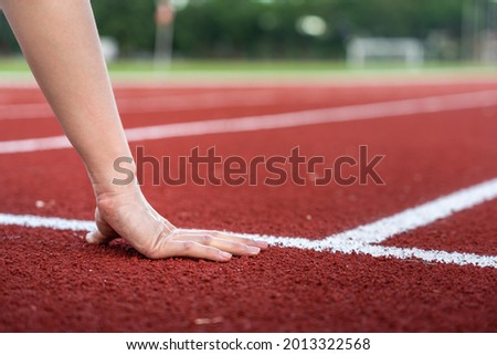 Action of a runner is placing hand on starting position of running racetrack, ready to start. Sport challenge competition abstract photo. 