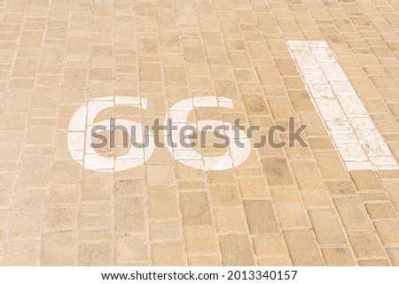 Empty outdoor parking on the street, brown tiles, number 66