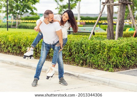 Couple enjoying activities together. Asian woman playing roller skating on her boyfriend's back at the park. 