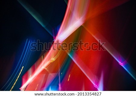 Abstract colorful background with red, white and yellow glowing lines of different thickness and curvature from city lights on a black background. The blur is intentional.