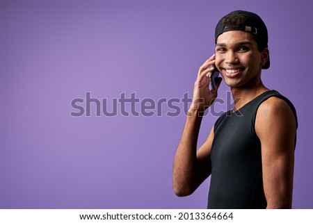 Portrait of transgender young man talking mobile in black casual dress. Latino trans gender model