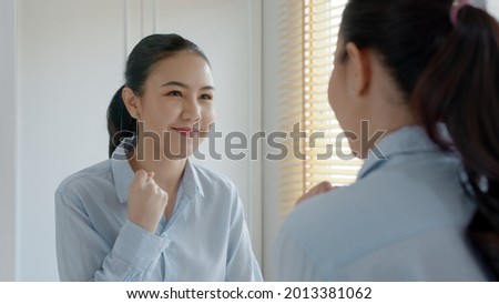 Young adult female asia people self love cheer up pep talk before job interview deep breathe inhale standing look in front of mirror smile at home in mental health care or work career stress relief. Royalty-Free Stock Photo #2013381062