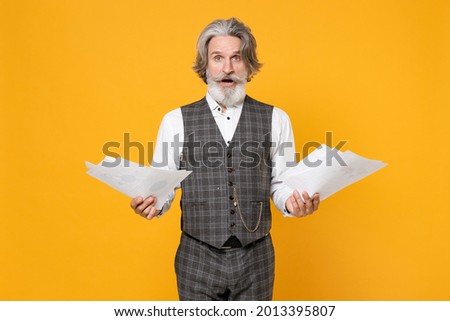 Shocked elderly gray-haired mustache bearded business man in checkered suit waistcoat white shirt hold papers document isolated on yellow background studio portrait. Achievement career wealth concept