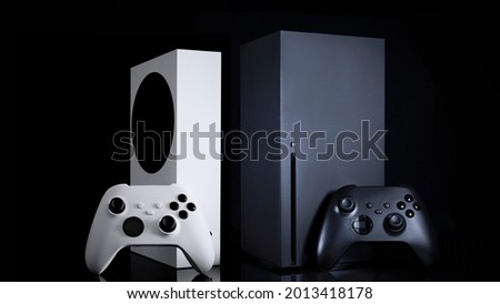 White and black game consoles and controllers with black background Royalty-Free Stock Photo #2013418178