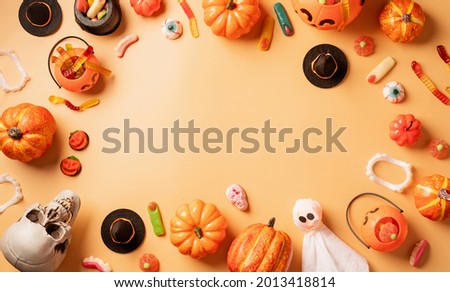 Halloween holiday decorations with pumpkins and candies top view on orange background with copy space