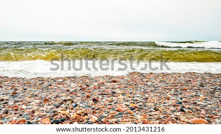 A lot of varieties of sea rocks on a beach against the background of a restless Baltic Sea with waves